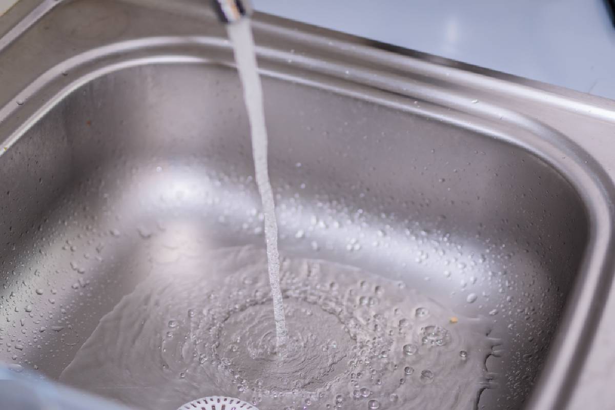 close up of water running from a tap into a stainless steel sink