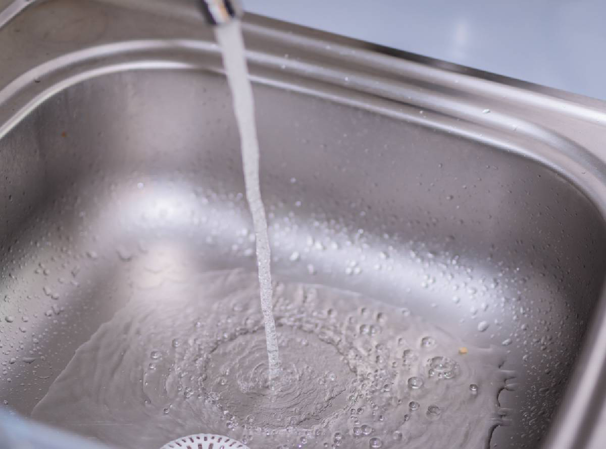 close up of water running from a tap into a stainless steel sink